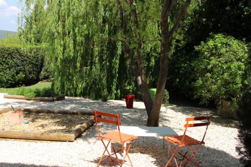 dos sillas y una mesa en un patio con un árbol en Chambre Cévennole, en Saint-Jean-de-Ceyrargues