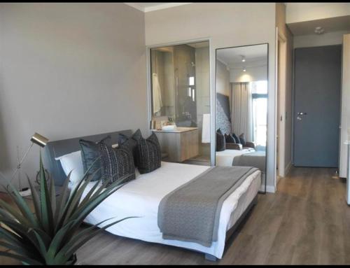 a bedroom with a large white bed and a large mirror at The Trilogy,Menlyn Maine in Pretoria
