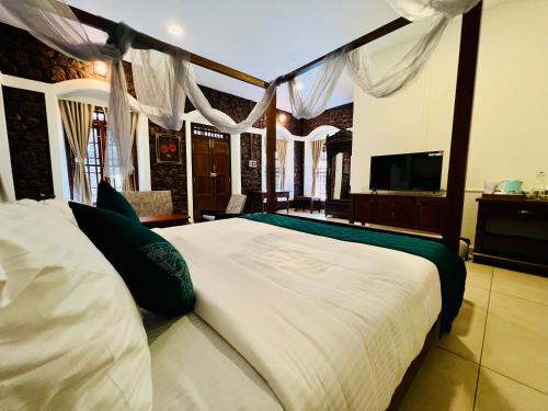 a bedroom with a large bed with white sheets and green pillows at Nature Sanctuary Urumbi Hills in Mundakāyam