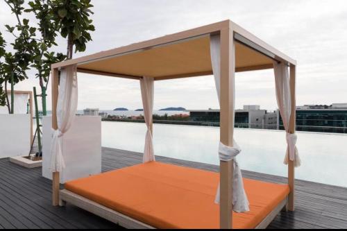 una cama naranja en una terraza junto a una piscina en Hstay Sutera Avenue 2Bedroom by Aida, en Kota Kinabalu