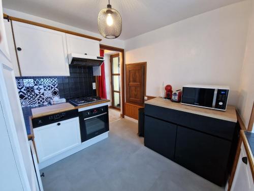 une cuisine avec une cuisinière et un micro-ondes dans l'établissement LES BOUVREUILS, à Les Deux Alpes