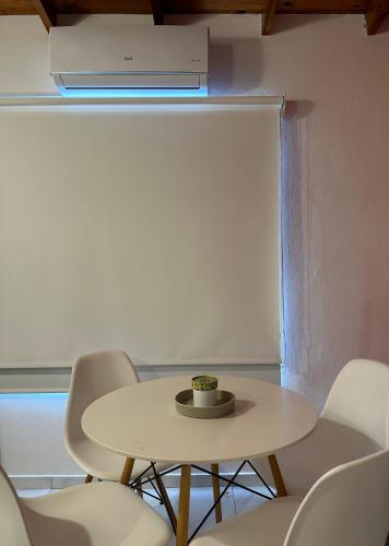 mesa blanca con sillas y TV en la pared en No reservar en San Bernardo