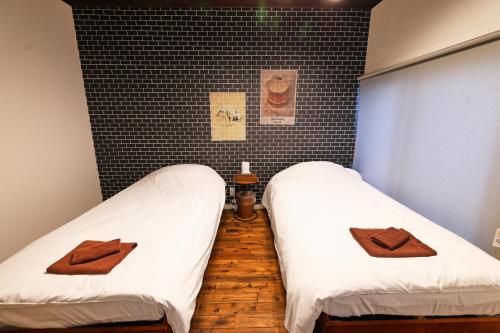 two beds in a room with white sheets and brown towels at 和氣会々都立家政 Wakiaiai Toritsukasei in Tokyo