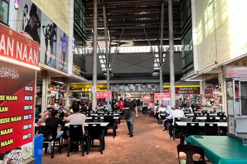 a person walking through a room with tables and chairs at Hana Guesthouse Metrocity (Nearby City Centre) in Kuching