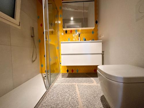 a bathroom with a toilet and a yellow wall at Charlie Home - Heart of Sardinia in Costa Paradiso