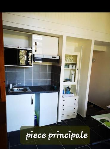 une cuisine avec des armoires blanches et un comptoir noir dans l'établissement COCON NATURE ENTRE LAC ET L OCEAN, à Carcans