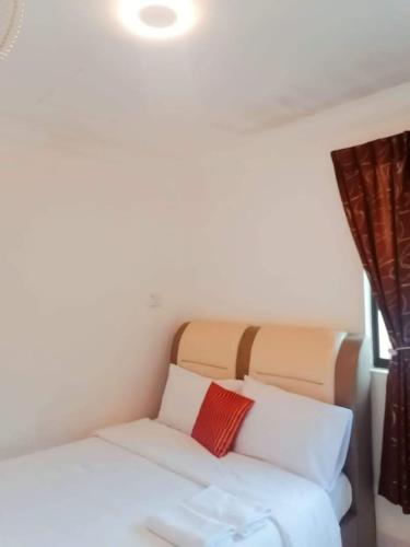 1 dormitorio con cama blanca y almohada roja en Secret Garden, en Kampong Alor Gajah