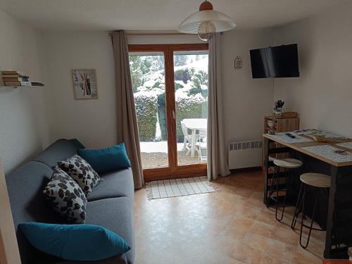 een woonkamer met een bank en een keuken met een tafel bij Charmant studio avec terrasse in Praz-sur-Arly