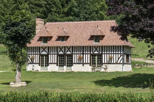 une maison ancienne avec un toit rouge sur un champ verdoyant dans l'établissement Gîte picturesque de 4 chambres, Pays d'Auge, à Cheffreville-Tonnencourt