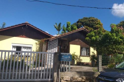 a yellow house with a fence in front of it at Casa Inteira em Jurerê In e vista panorâmica in Florianópolis