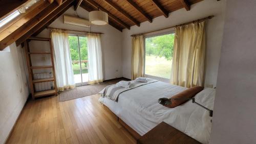 a bedroom with a large bed and large windows at Chacra Esaki in El Bolsón