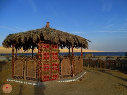 a hut with a thatched roof on the beach at flamingo camp in Dār as Salām