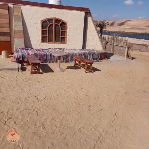 a building with two benches and a table in the desert at flamingo camp in Dār as Salām