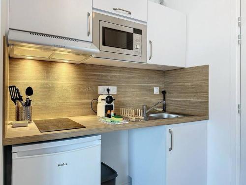 uma cozinha com um lavatório e um micro-ondas em Escale Dinardaise - Garage - 2km de la mer em Dinard