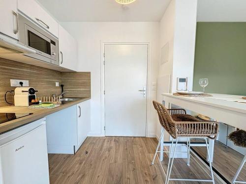 uma cozinha com um balcão e duas cadeiras em Escale Dinardaise - Garage - 2km de la mer em Dinard
