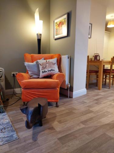 una sala de estar con una silla naranja y una mesa en The Veterinary @ Kildare Village, en Kildare