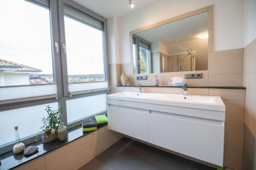 ein Badezimmer mit einem weißen Waschbecken und einem Spiegel in der Unterkunft Odenwaldblick in Lützelbach