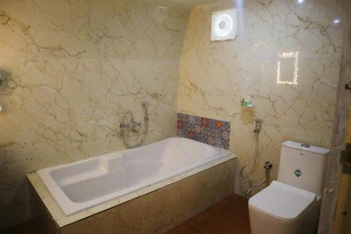 a bathroom with a bath tub and a toilet at Royal Adventures in Kodaikānāl