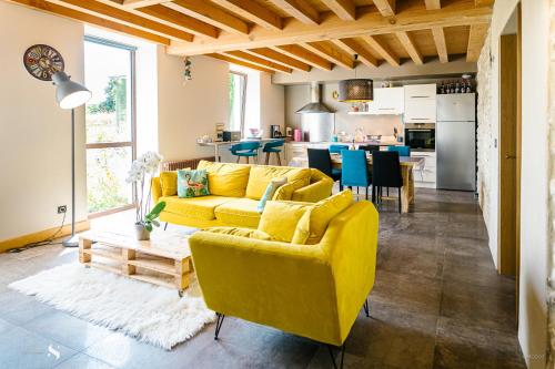 un salon avec un canapé jaune et une cuisine dans l'établissement Au Pied des Vignes, à Saint-Pourçain-sur-Sioule