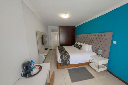 a hotel room with a bed and a television at Green Lagoon Guest House Tawana in Gaborone