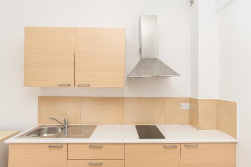 a kitchen with wooden cabinets and a sink at Flora Hotel Apartments in Protaras