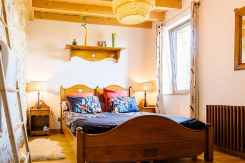 - une chambre avec un lit en bois et des oreillers colorés dans l'établissement Au Pied des Vignes, à Saint-Pourçain-sur-Sioule