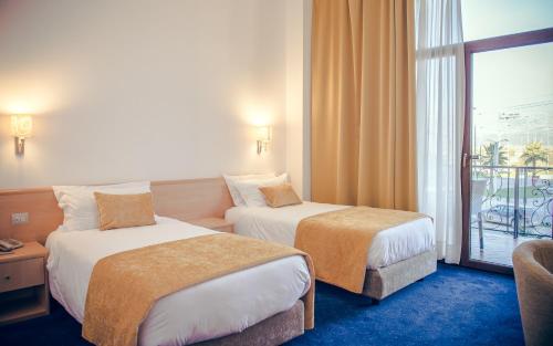 a hotel room with two beds and a balcony at Hotel Airport Tirana in Rinas
