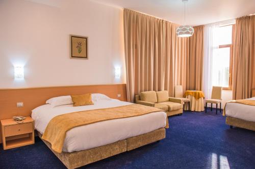 une chambre d'hôtel avec un lit et une chaise dans l'établissement Hotel Airport Tirana, à Rinas