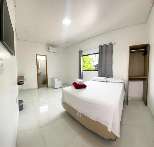 a white bedroom with a large bed and a television at Pousada Amazônia in Rio Branco