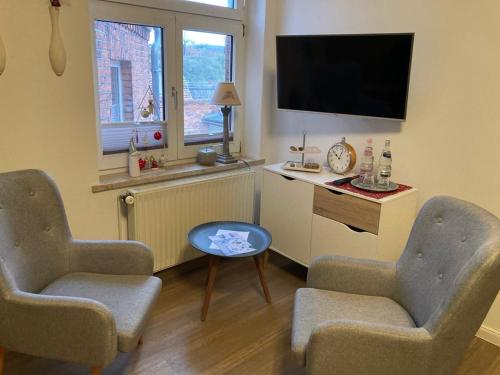 a living room with two chairs and a flat screen tv at Bilderbuchcafe - Ferien Apartment NO 5 - Markt 7 in Havelberg