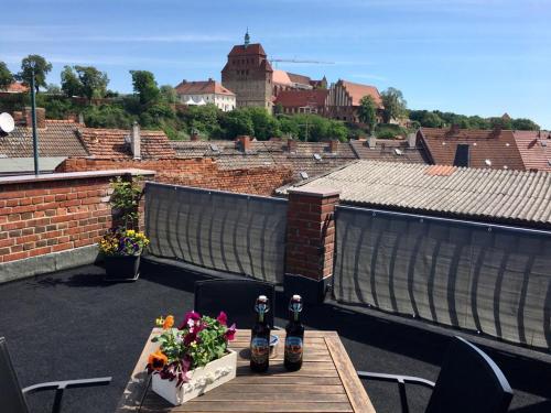 two people sitting on a balcony with flowers on a table at Das BilderbuchCafe - Ferien Apartment NO 5 - Markt 7 in Havelberg