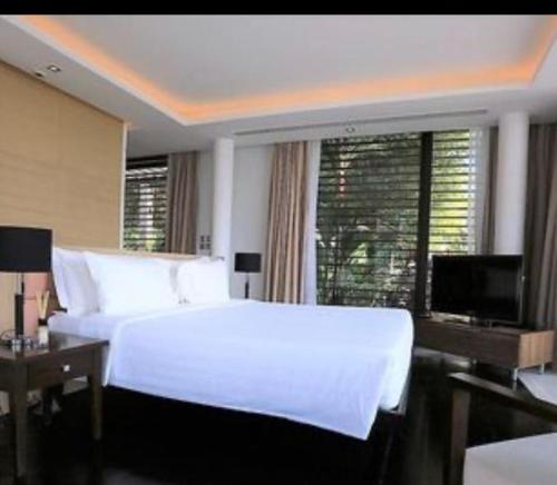 1 dormitorio con 1 cama blanca grande y TV en Aurora Villa, en Phuket