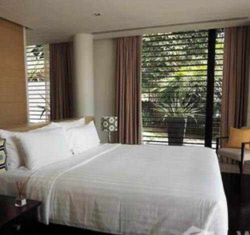 a bedroom with a white bed and a large window at Aurora Villa in Phuket Town