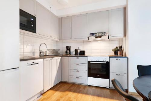 a white kitchen with white cabinets and a table at Guestly Homes - 3BR City Charm in Piteå