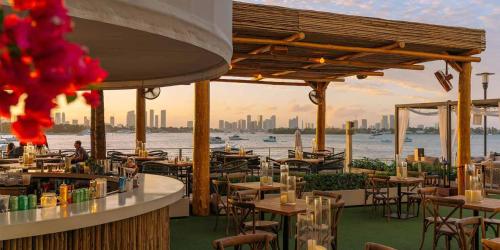 a restaurant with tables and chairs and a view of the water at 1100 West South Beach Luxe Miami Condos by Joe Semary in Miami Beach