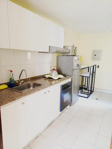 a kitchen with a sink and a refrigerator at Departamento completo cerca de Embajada Americana in Quito