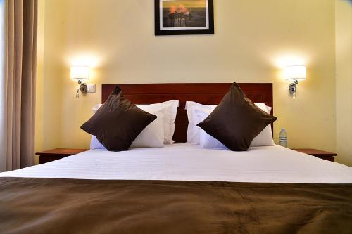 a bedroom with a large bed with white sheets and pillows at ENTEBBE STAY Apart-Hotel in Entebbe