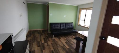 a living room with a black leather couch and a window at Apartamento Vista al Estrecho in Punta Arenas