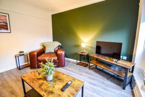 a living room with a leather chair and a flat screen tv at Woodcock House 3 Bedrooms Workstays UK in Lackenby