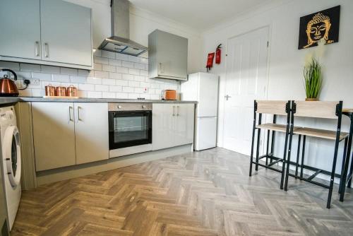 a kitchen with white appliances and a wooden floor at Woodcock House 3 Bedrooms Workstays UK in Lackenby