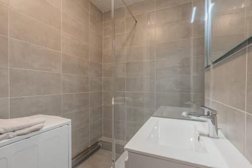 La salle de bains est pourvue d'un lavabo blanc et d'une douche. dans l'établissement Le cocon, à Fontaine