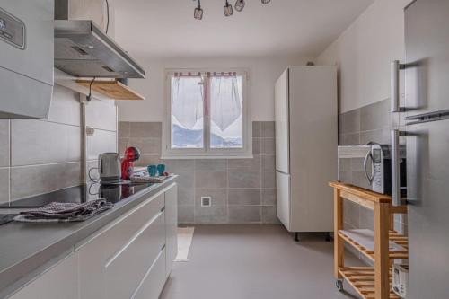 une cuisine avec un réfrigérateur blanc et une fenêtre dans l'établissement Le cocon, à Fontaine