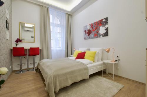 1 dormitorio con cama blanca y almohadas rojas y amarillas en St. King 11 Apartments, en Budapest