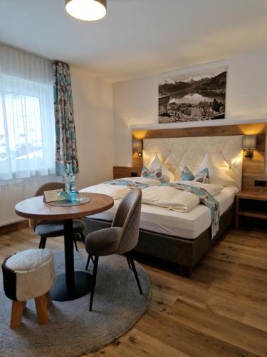 a hotel room with a bed and a table and a chair at Pension Claudia Zell am See in Zell am See