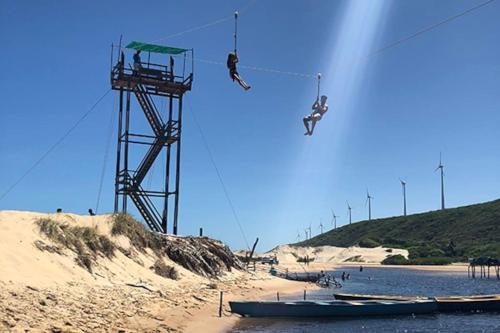 two people on a zip line over a beach at Paz, arte, beleza e natureza na praia de Sagi in Baía Formosa