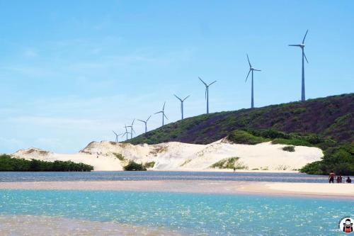 a beach with windmills on top of a hill at Paz, arte, beleza e natureza na praia de Sagi in Baía Formosa