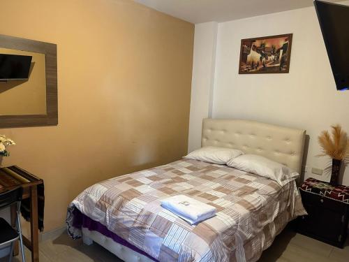 Dormitorio pequeño con cama con manta en Hostal Aly en Otavalo