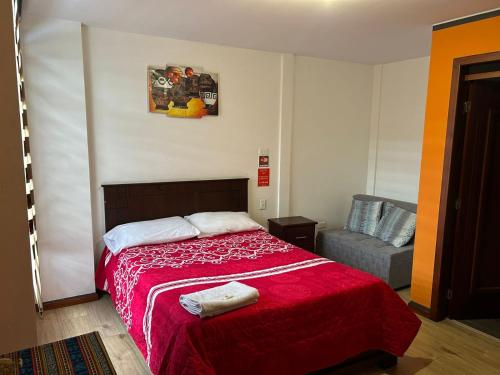a bedroom with a red bed and a couch at Hostal Aly in Otavalo