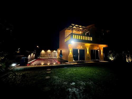 a house with lights on the front of it at night at The Orchard House in Raichak