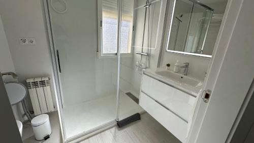 a white bathroom with a shower and a sink at Ático en el centro de Granada in Granada